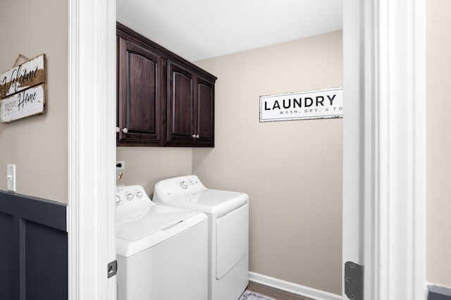 clothes washing area with washer and dryer, cabinet space, and baseboards