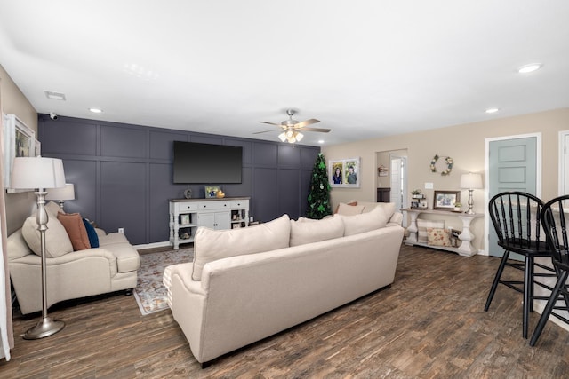 living room featuring recessed lighting, visible vents, dark wood-style floors, and a decorative wall