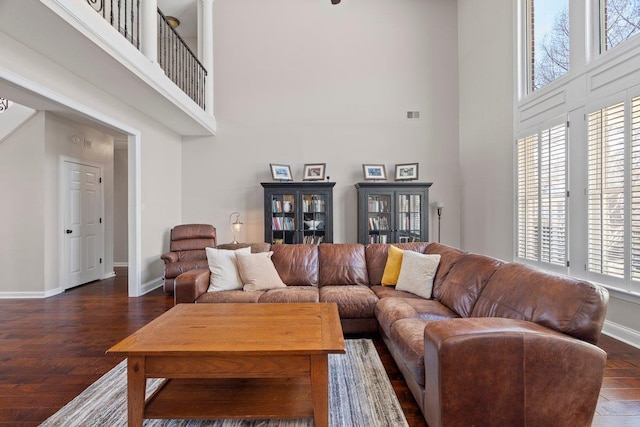 living area featuring visible vents, baseboards, a towering ceiling, and dark wood-style flooring