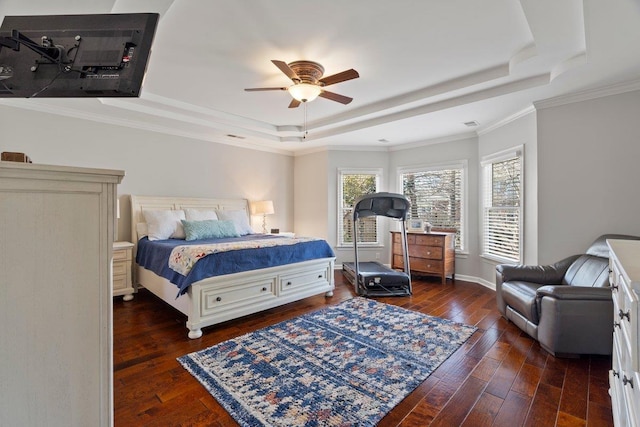 bedroom featuring baseboards, ornamental molding, hardwood / wood-style flooring, a raised ceiling, and a ceiling fan