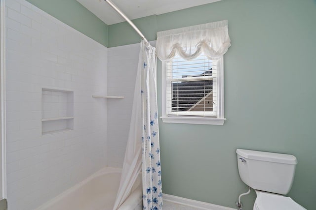 bathroom featuring baseboards, toilet, and shower / tub combo