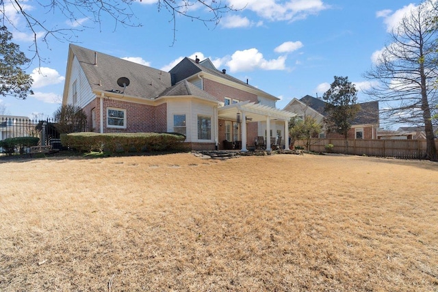 view of front facade with fence, brick siding, a front yard, and a pergola