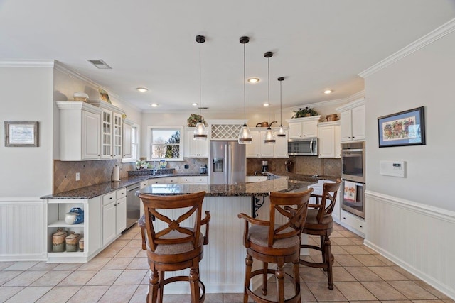 kitchen with appliances with stainless steel finishes, light tile patterned flooring, and wainscoting