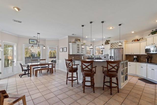 kitchen featuring visible vents, dark countertops, stainless steel appliances, crown molding, and light tile patterned floors