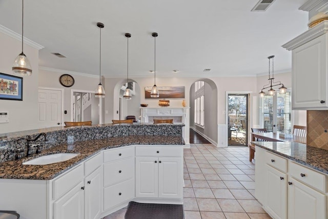 kitchen with arched walkways, visible vents, light tile patterned flooring, and a sink