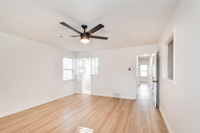 unfurnished room featuring plenty of natural light, a ceiling fan, baseboards, and light wood finished floors