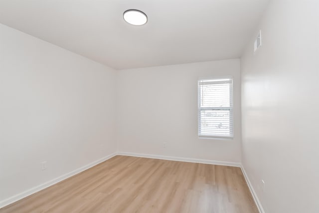 empty room with light wood-type flooring, baseboards, and visible vents