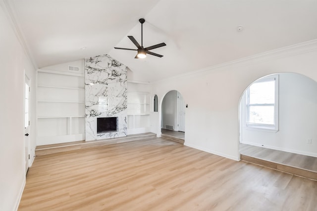 unfurnished living room with light wood-type flooring, visible vents, built in shelves, a premium fireplace, and ceiling fan