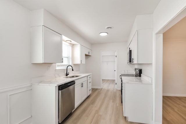 kitchen with visible vents, white cabinetry, stainless steel appliances, and a sink