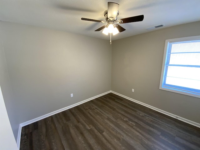 spare room with visible vents, baseboards, dark wood-type flooring, and ceiling fan