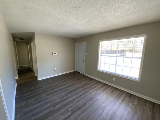 spare room with dark wood-style floors, baseboards, and a textured ceiling