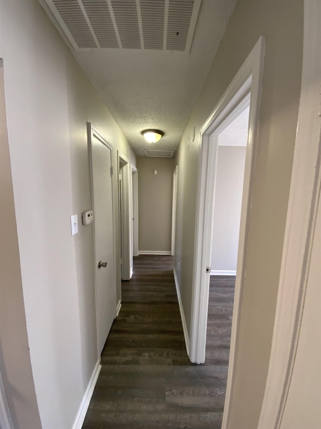 hallway featuring wood finished floors, baseboards, and a textured ceiling