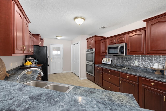 kitchen featuring visible vents, a sink, appliances with stainless steel finishes, light floors, and dark brown cabinets