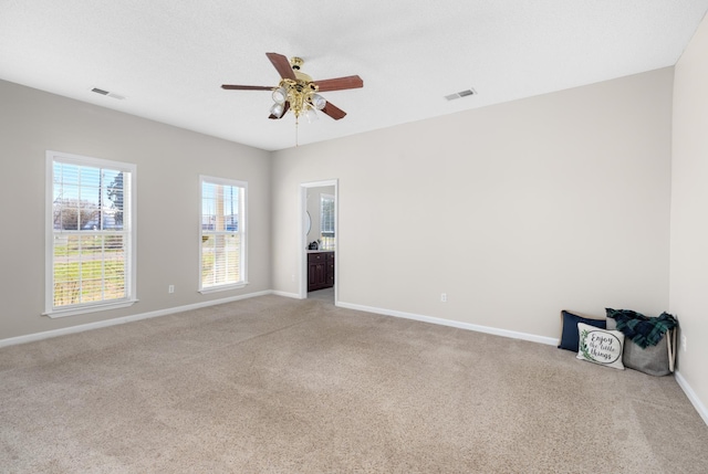 spare room featuring visible vents, light colored carpet, and baseboards