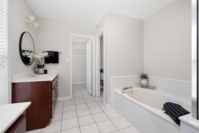 full bathroom with tile patterned flooring, a walk in closet, baseboards, a garden tub, and vanity