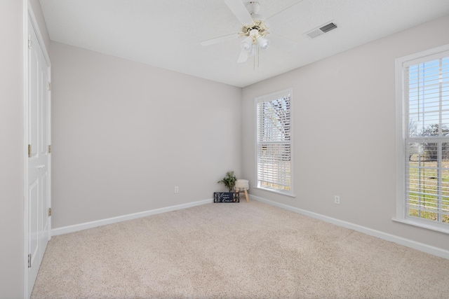 carpeted spare room featuring a ceiling fan, baseboards, and visible vents