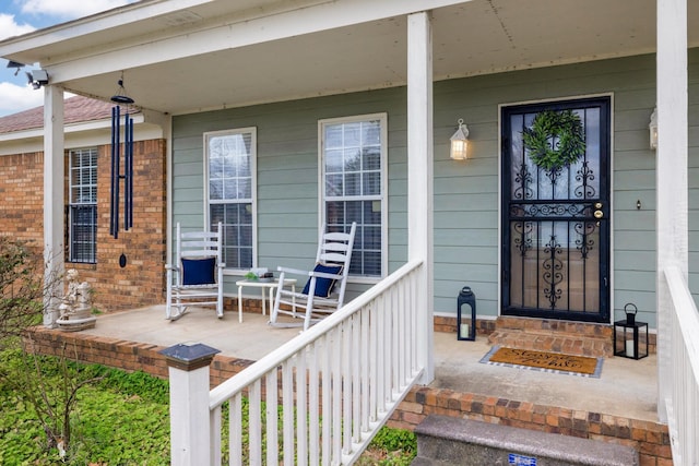 entrance to property with brick siding and a porch