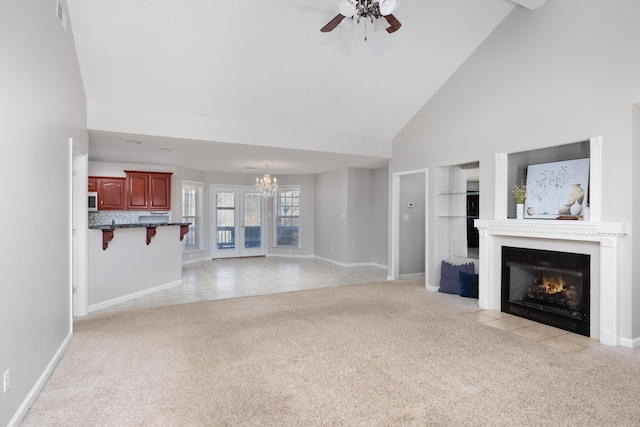 unfurnished living room with light carpet, high vaulted ceiling, a fireplace with flush hearth, ceiling fan with notable chandelier, and built in features