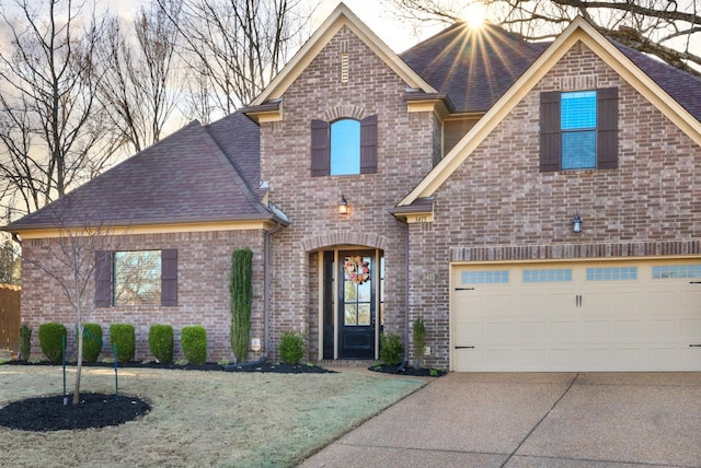 view of front of property featuring brick siding, concrete driveway, a front yard, and a shingled roof