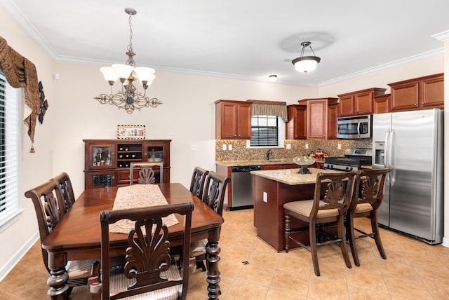 kitchen featuring a kitchen island, an inviting chandelier, ornamental molding, appliances with stainless steel finishes, and backsplash