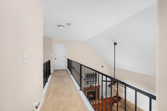 hall featuring visible vents, light carpet, baseboards, and vaulted ceiling