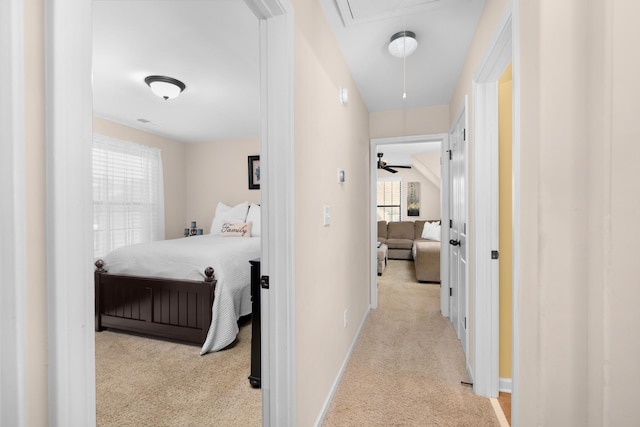 hall with attic access, baseboards, and carpet floors