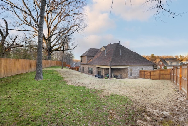 back of house featuring a yard, brick siding, and a fenced backyard