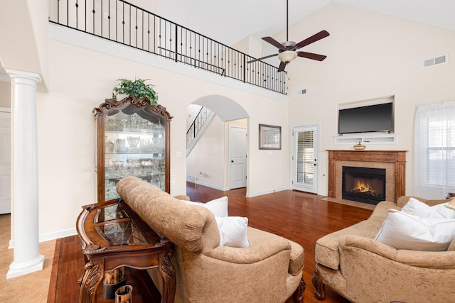 living area with visible vents, a fireplace with flush hearth, wood finished floors, and decorative columns