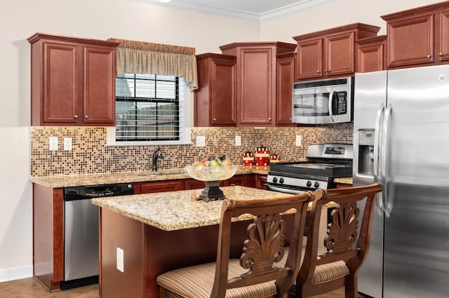 kitchen with a breakfast bar, a sink, backsplash, appliances with stainless steel finishes, and crown molding