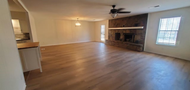 unfurnished living room with visible vents, a fireplace, a ceiling fan, and wood finished floors