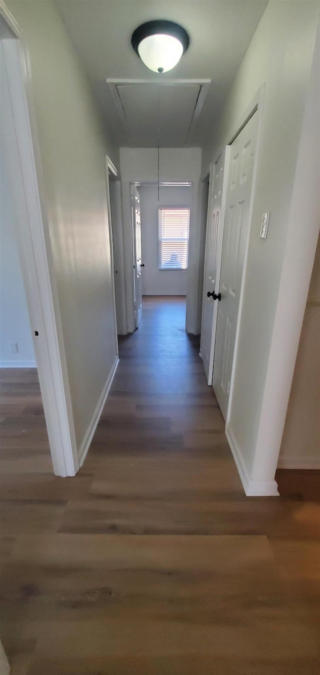 hall with attic access, wood finished floors, and baseboards