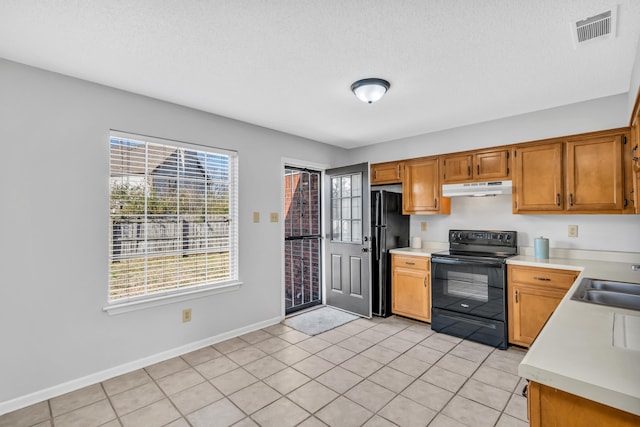 kitchen featuring visible vents, a sink, black appliances, light countertops, and under cabinet range hood