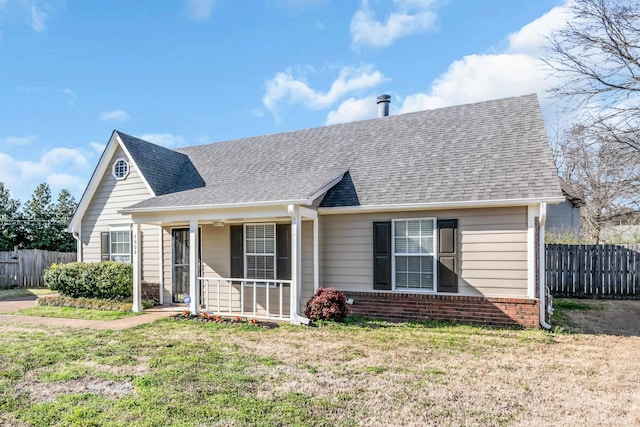 view of front of property featuring fence, covered porch, a front yard, a shingled roof, and brick siding