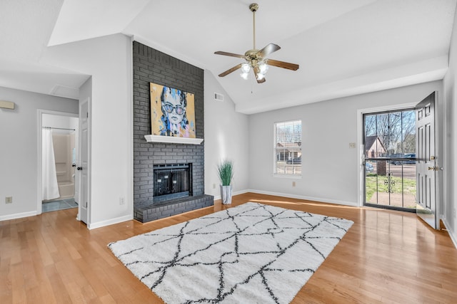 living area featuring a fireplace, baseboards, lofted ceiling, and wood finished floors