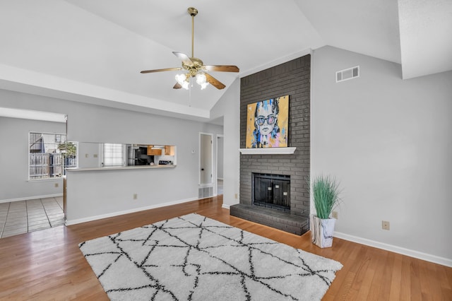 living area with visible vents, lofted ceiling, wood finished floors, and a fireplace