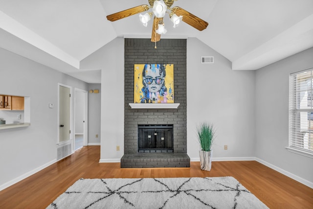 living room with visible vents, a fireplace, and wood finished floors