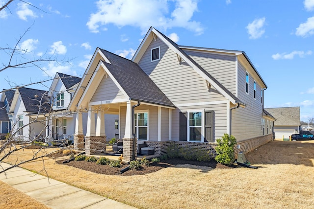 view of front of property with covered porch, brick siding, a residential view, and a shingled roof