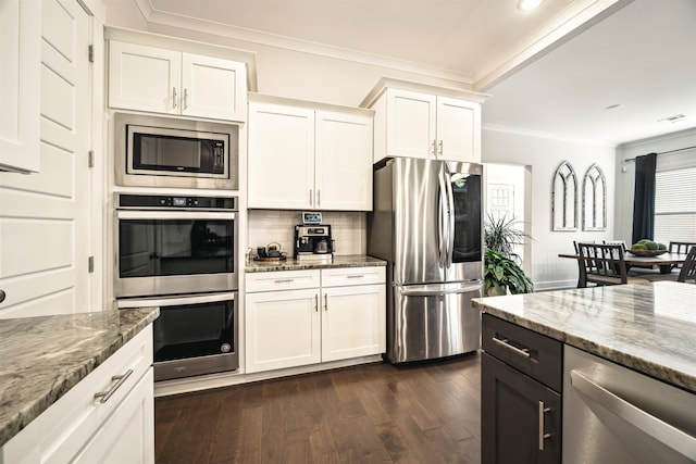 kitchen featuring stone countertops, stainless steel appliances, dark wood-type flooring, and ornamental molding