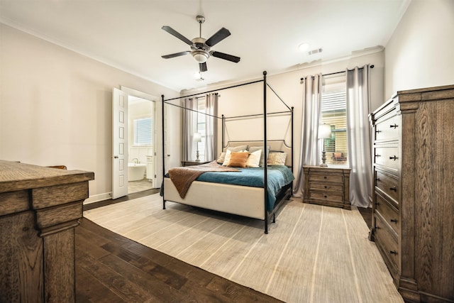 bedroom featuring visible vents, crown molding, baseboards, light wood-type flooring, and ensuite bath