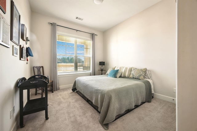 bedroom featuring visible vents, light colored carpet, and baseboards