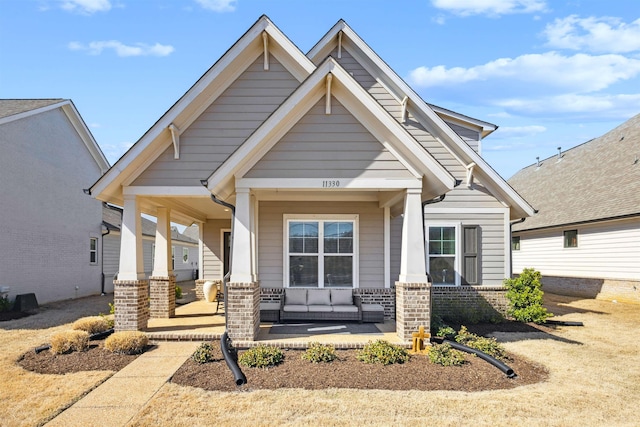 craftsman inspired home with an outdoor hangout area, brick siding, and a porch