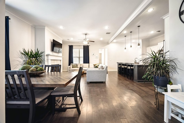 dining space featuring visible vents, crown molding, dark wood finished floors, recessed lighting, and a tile fireplace