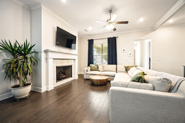 living area with dark wood finished floors, a tiled fireplace, baseboards, and ornamental molding