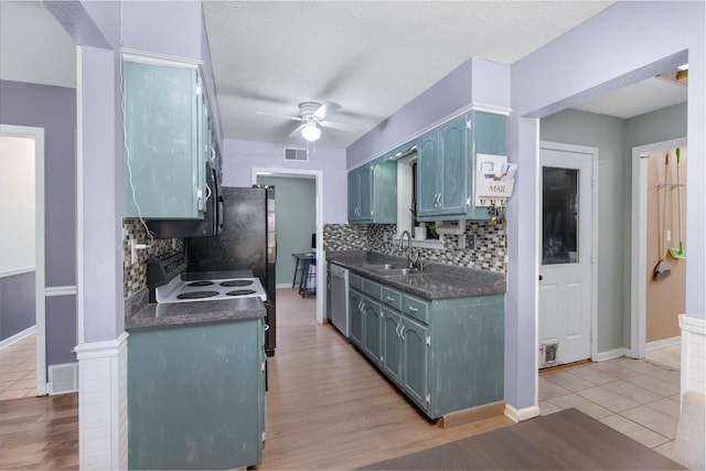 kitchen featuring visible vents, ceiling fan, a sink, dark countertops, and blue cabinets