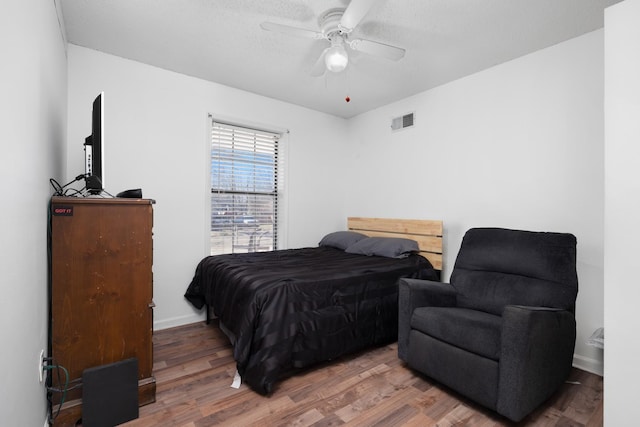 bedroom featuring visible vents, a ceiling fan, a textured ceiling, wood finished floors, and baseboards