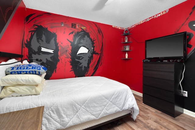 bedroom with ceiling fan, baseboards, a textured ceiling, and wood finished floors