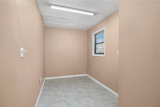 empty room featuring attic access and baseboards