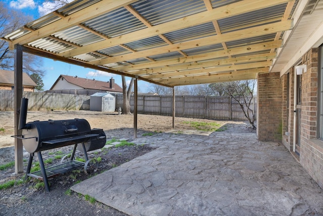 view of patio / terrace with an outbuilding, a grill, a storage shed, and a fenced backyard