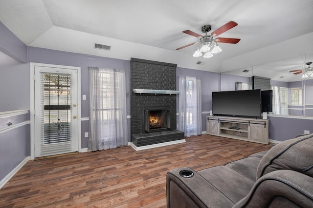 living area featuring a ceiling fan, wood finished floors, visible vents, and baseboards