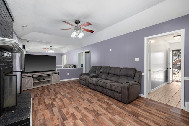 living room with visible vents, wood finished floors, baseboards, lofted ceiling, and ceiling fan